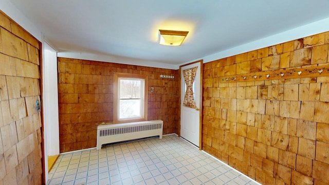 unfurnished room featuring radiator and wooden walls