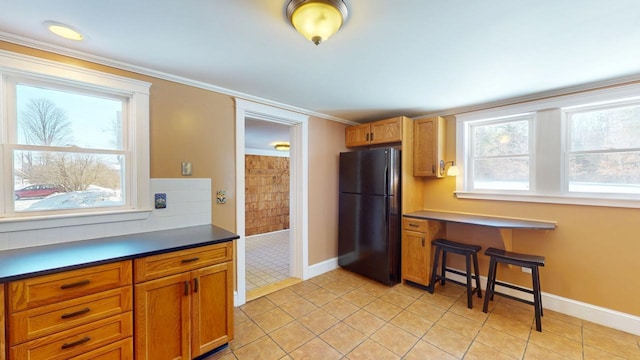 kitchen featuring dark countertops, built in study area, freestanding refrigerator, and baseboards