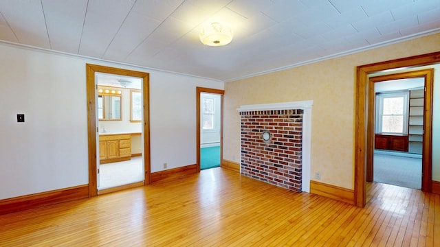 empty room with baseboard heating, baseboards, light wood-style floors, and ornamental molding