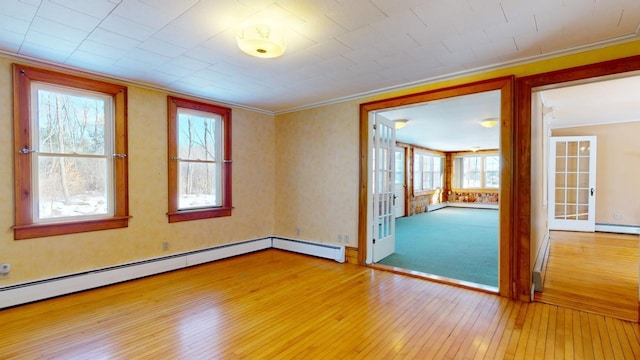 empty room with hardwood / wood-style flooring, a baseboard heating unit, french doors, crown molding, and baseboard heating