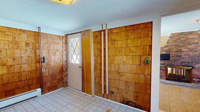 doorway to outside with tile patterned flooring, wood walls, a fireplace, and a baseboard heating unit