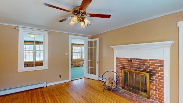 unfurnished living room featuring a wealth of natural light, baseboard heating, ornamental molding, and hardwood / wood-style flooring