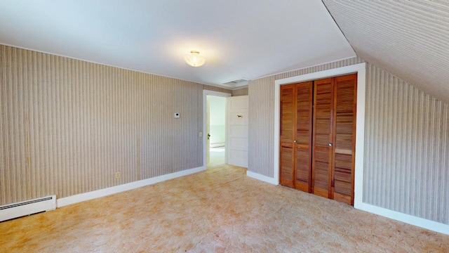 unfurnished bedroom featuring a closet, carpet flooring, a baseboard heating unit, and baseboards