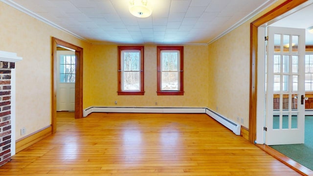 spare room featuring light wood-type flooring, baseboard heating, and crown molding