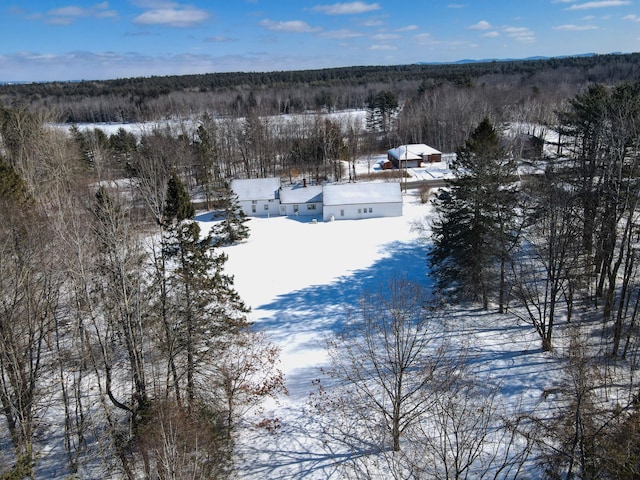 snowy aerial view featuring a wooded view