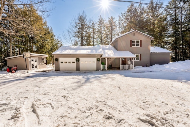 view of front of home with a garage, covered porch, driveway, and an outbuilding