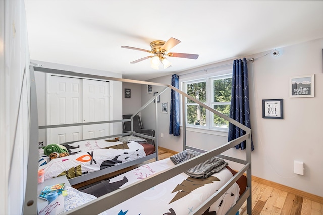 bedroom with ceiling fan, a closet, wood finished floors, and baseboards