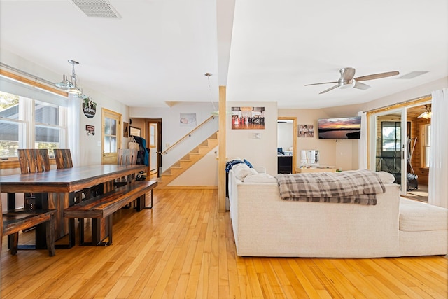 living room featuring stairs, visible vents, plenty of natural light, and light wood-style flooring