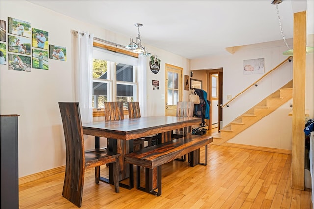 dining room featuring baseboards, stairway, and light wood finished floors