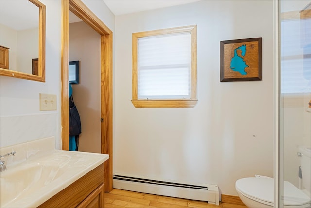 bathroom with toilet, a baseboard radiator, wood finished floors, and vanity