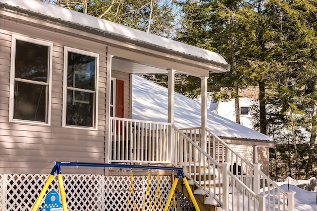 view of snowy exterior with stairway and metal roof