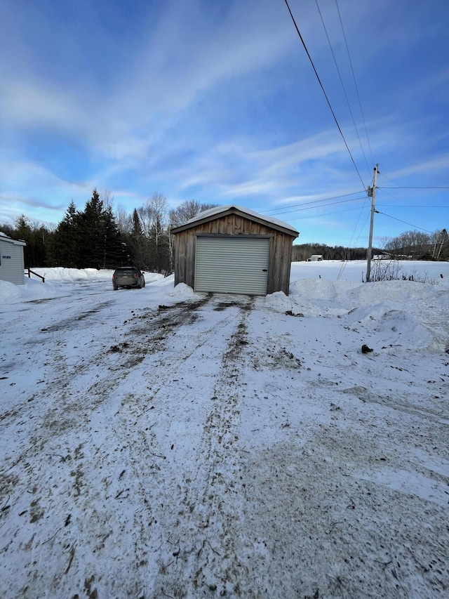 yard covered in snow featuring a garage and an outdoor structure