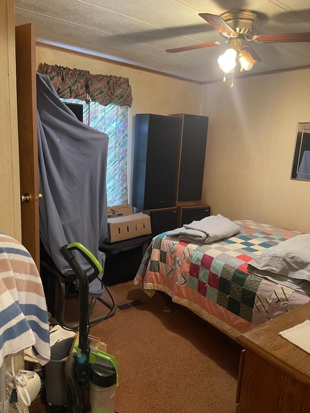 carpeted bedroom featuring a ceiling fan and a decorative wall