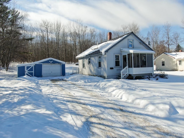 view of front of home with a garage, an outdoor structure, and a sunroom