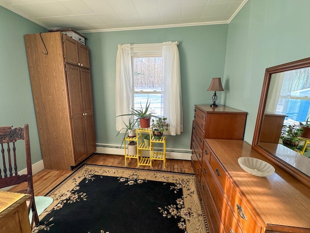 interior space with ornamental molding, light wood-type flooring, and a baseboard radiator