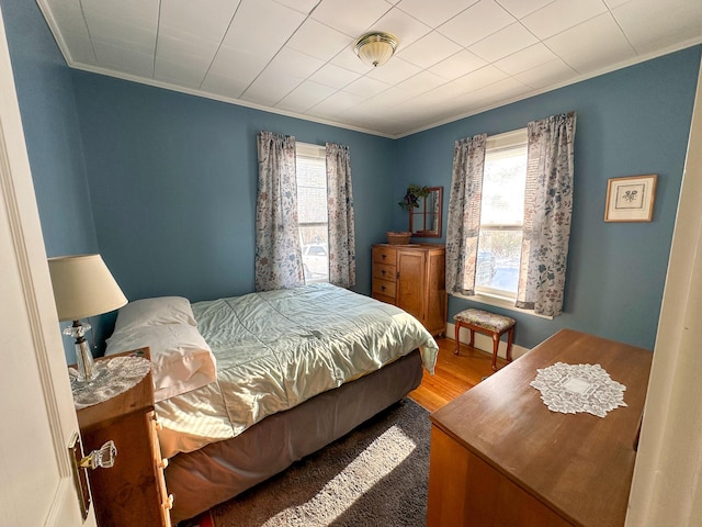 bedroom featuring multiple windows, wood-type flooring, and ornamental molding