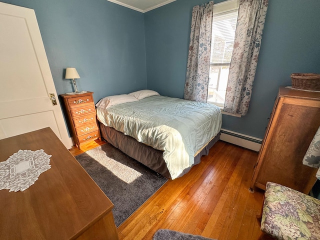 bedroom with crown molding, a baseboard heating unit, and dark hardwood / wood-style floors