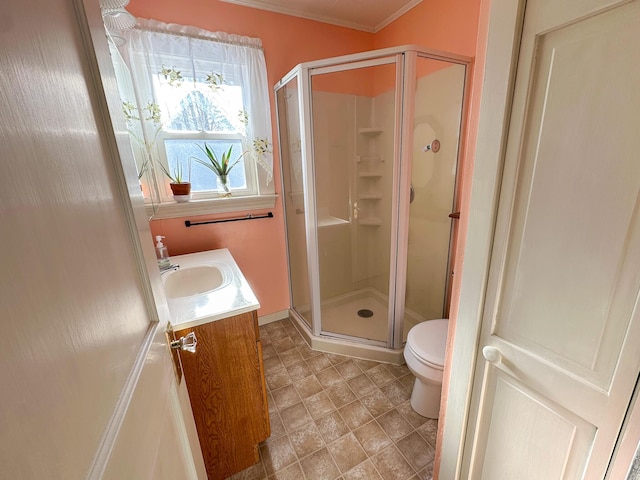 bathroom featuring a shower with door, vanity, ornamental molding, and toilet