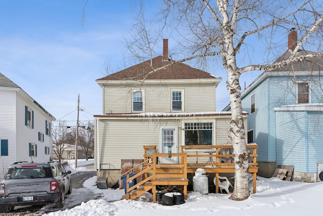 snow covered rear of property with a wooden deck