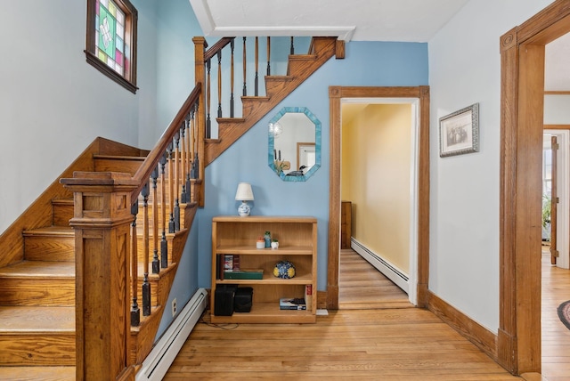 stairway with a baseboard heating unit and hardwood / wood-style floors