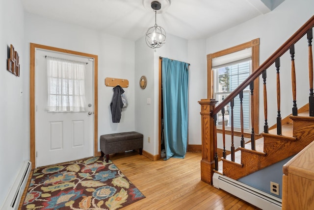 foyer entrance with light wood-type flooring, a notable chandelier, and baseboard heating