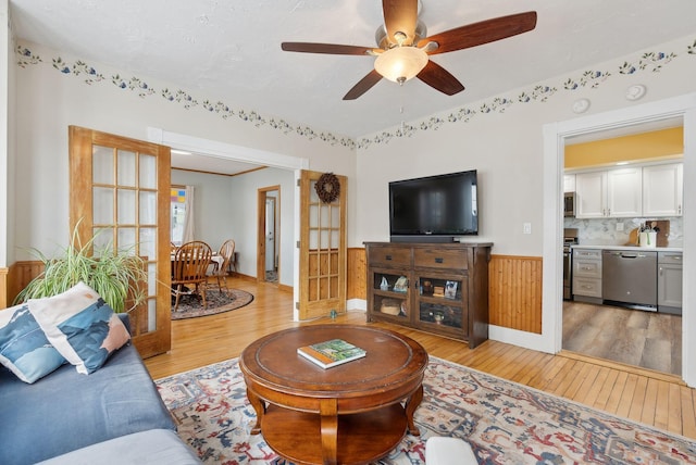 living room with ceiling fan, wooden walls, and light hardwood / wood-style floors