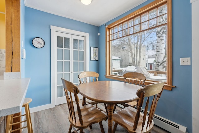 dining area featuring hardwood / wood-style flooring, a baseboard radiator, and ornamental molding