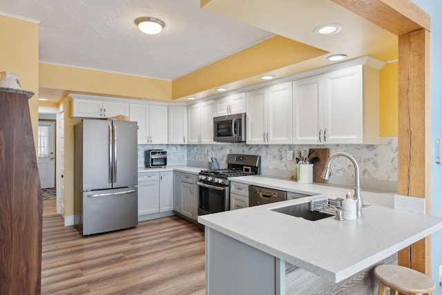 kitchen with appliances with stainless steel finishes, sink, a breakfast bar area, white cabinets, and kitchen peninsula