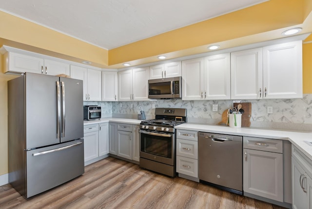 kitchen featuring stainless steel appliances, white cabinetry, gray cabinets, and backsplash