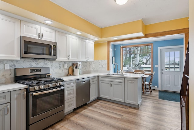 kitchen featuring baseboard heating, stainless steel appliances, sink, and white cabinets