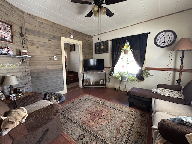 living room featuring dark hardwood / wood-style flooring, wooden walls, and ceiling fan