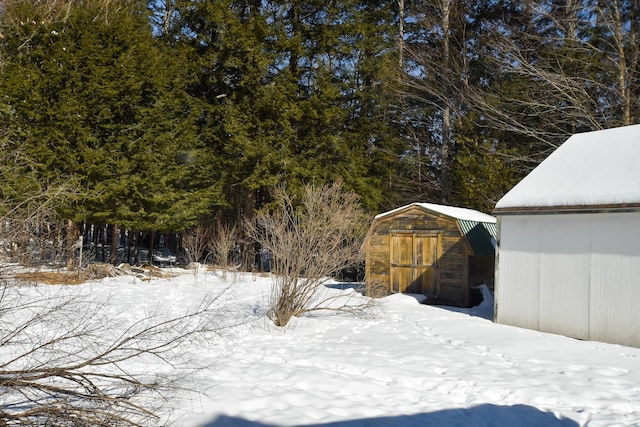 yard layered in snow featuring a storage shed