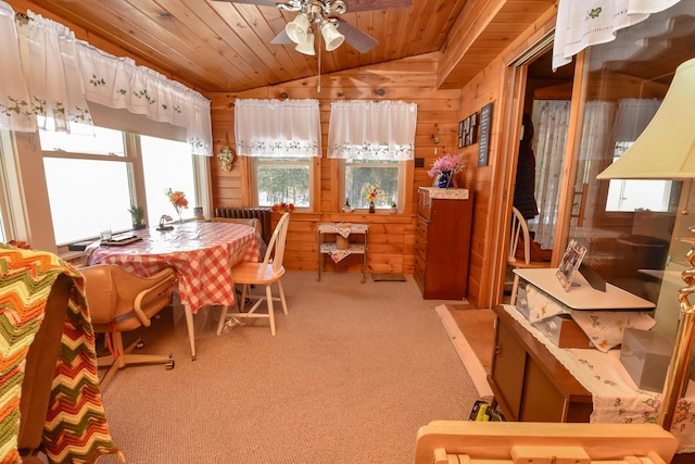 dining area with ceiling fan, light carpet, vaulted ceiling, wooden ceiling, and wood walls