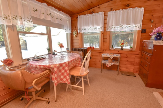 carpeted dining space with vaulted ceiling, wood ceiling, and wood walls