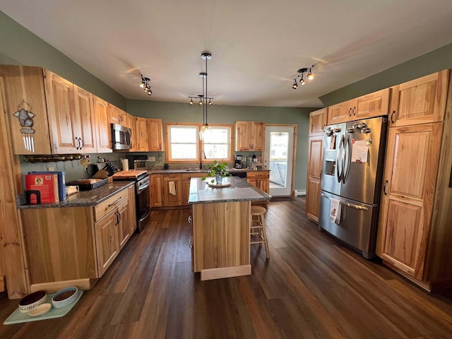 kitchen featuring dark wood-type flooring, a breakfast bar, decorative light fixtures, a center island, and appliances with stainless steel finishes