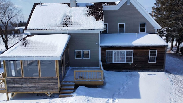 snow covered house featuring a sunroom