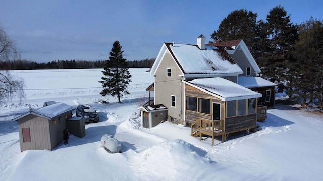 snow covered property featuring a sunroom