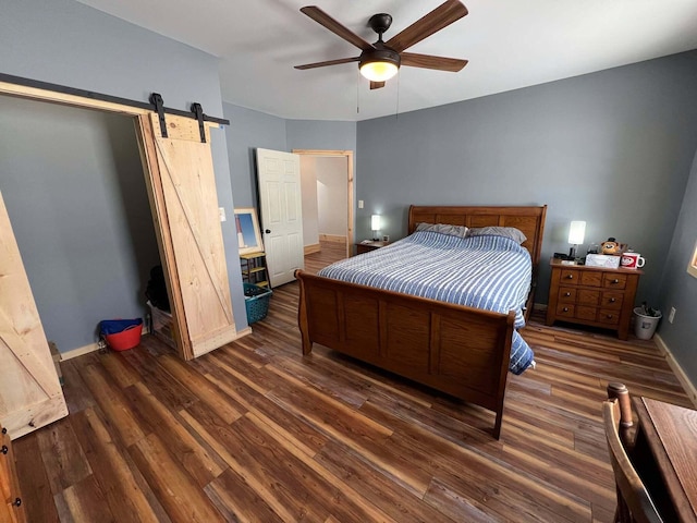 bedroom featuring ceiling fan, a barn door, and dark hardwood / wood-style flooring