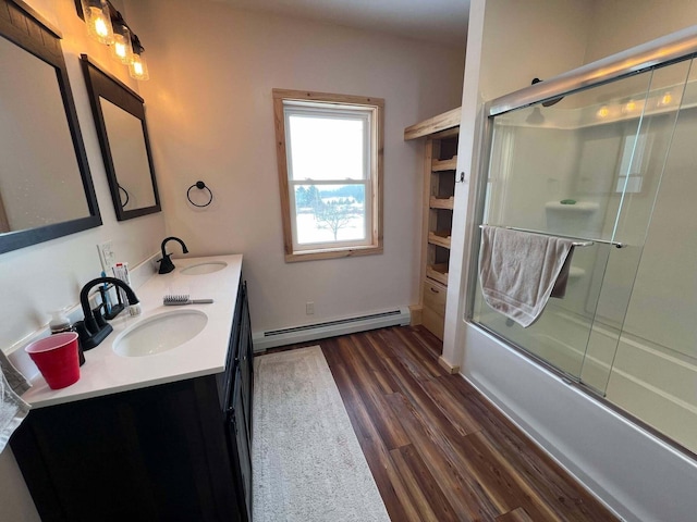 bathroom with vanity, hardwood / wood-style flooring, combined bath / shower with glass door, and baseboard heating