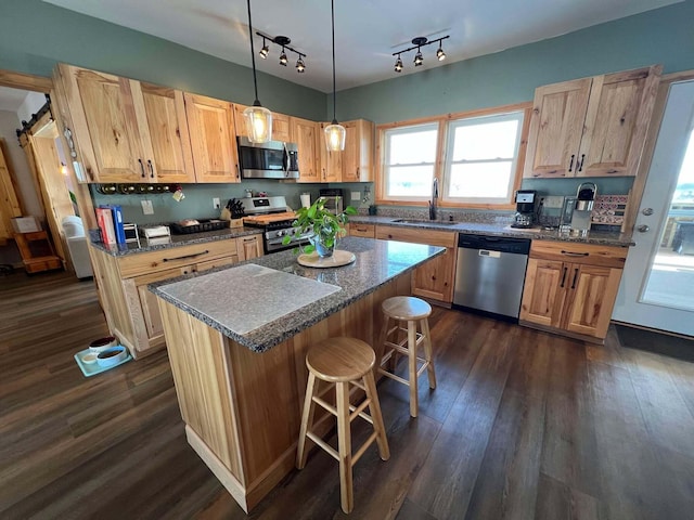 kitchen with appliances with stainless steel finishes, sink, a breakfast bar area, hanging light fixtures, and a center island