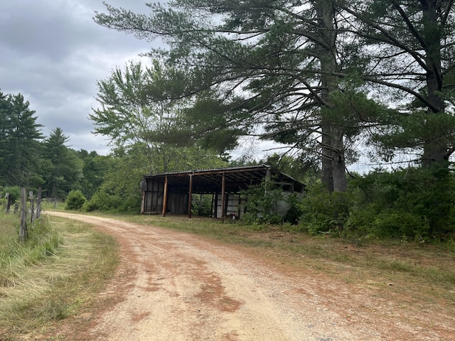 83 River Rd, Hiram, ME 04041 - view of dirt / gravel road featuring an outbuilding and a wooded view