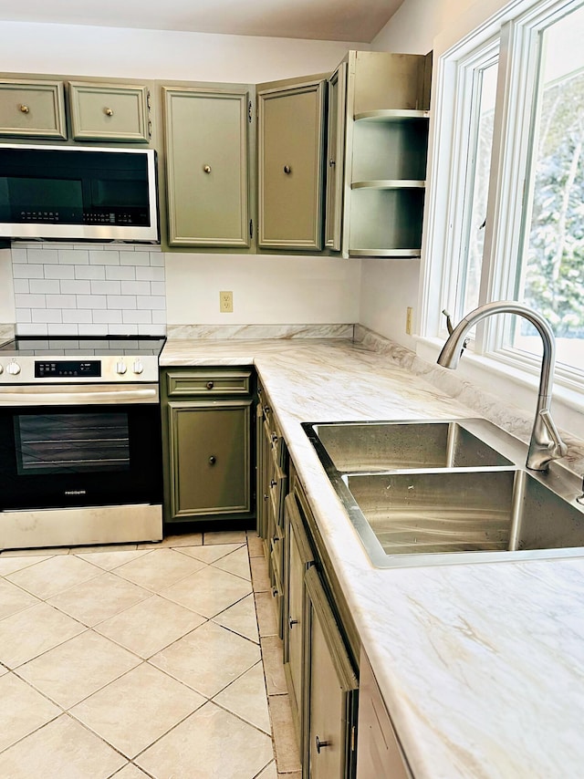 kitchen featuring stainless steel appliances, light countertops, open shelves, light tile patterned floors, and a sink