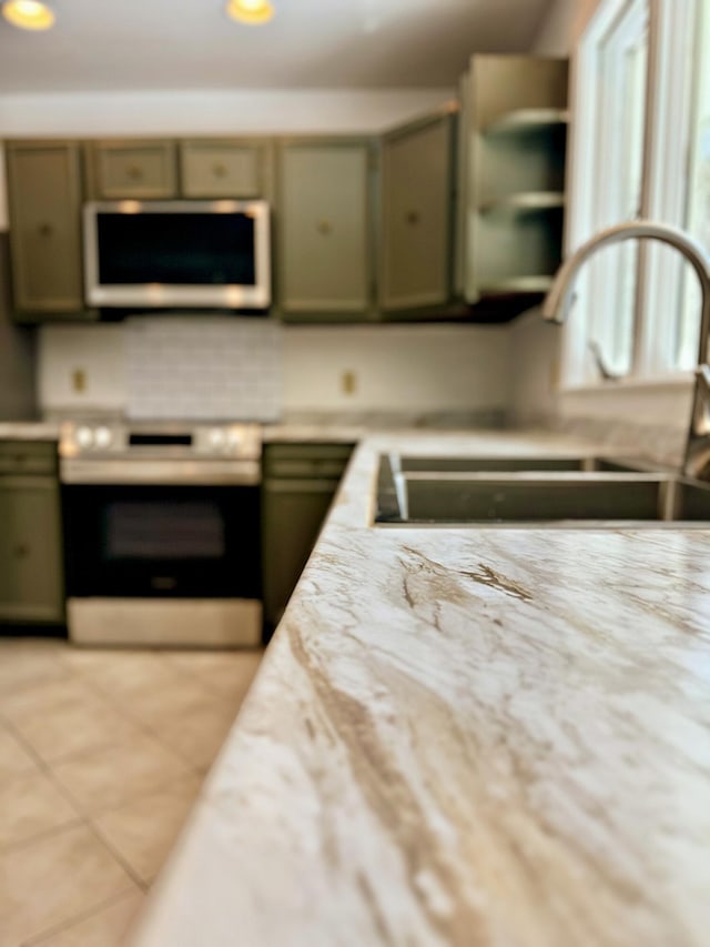 kitchen featuring recessed lighting, a sink, light tile patterned flooring, green cabinets, and stainless steel stove