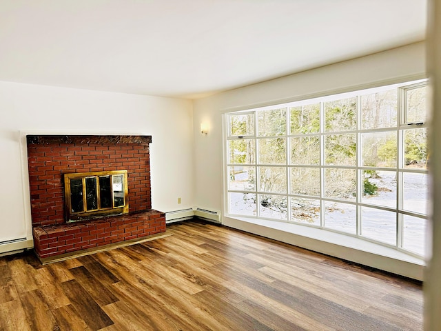 unfurnished living room featuring a baseboard heating unit, a brick fireplace, wood finished floors, and baseboard heating