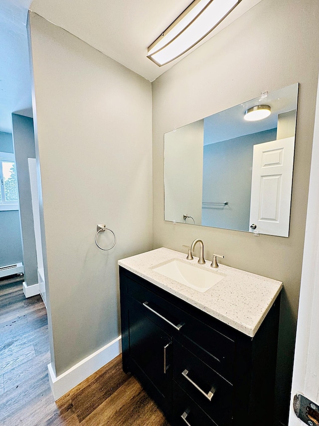 bathroom with baseboard heating, baseboards, vanity, and wood finished floors