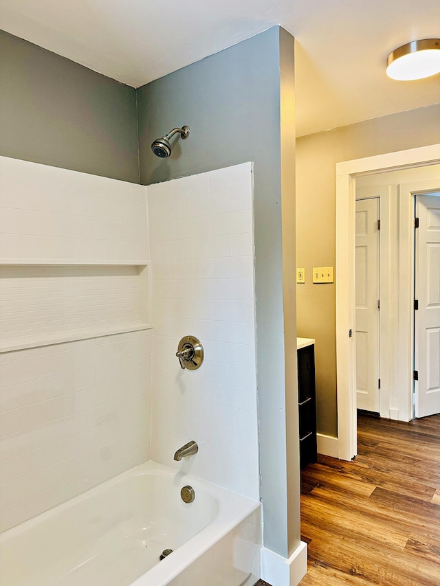 full bathroom featuring washtub / shower combination, wood finished floors, vanity, and baseboards