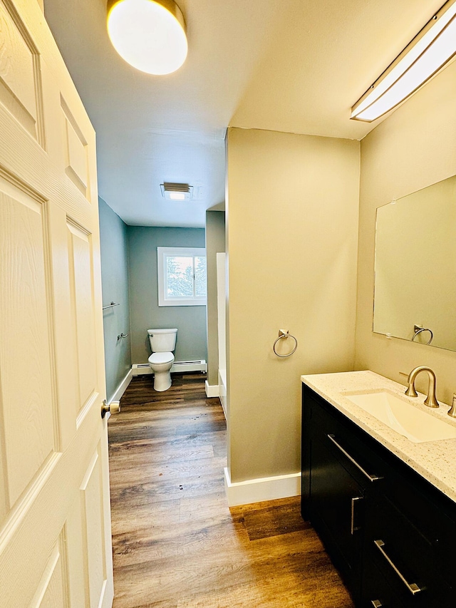 bathroom with toilet, vanity, wood finished floors, and baseboards