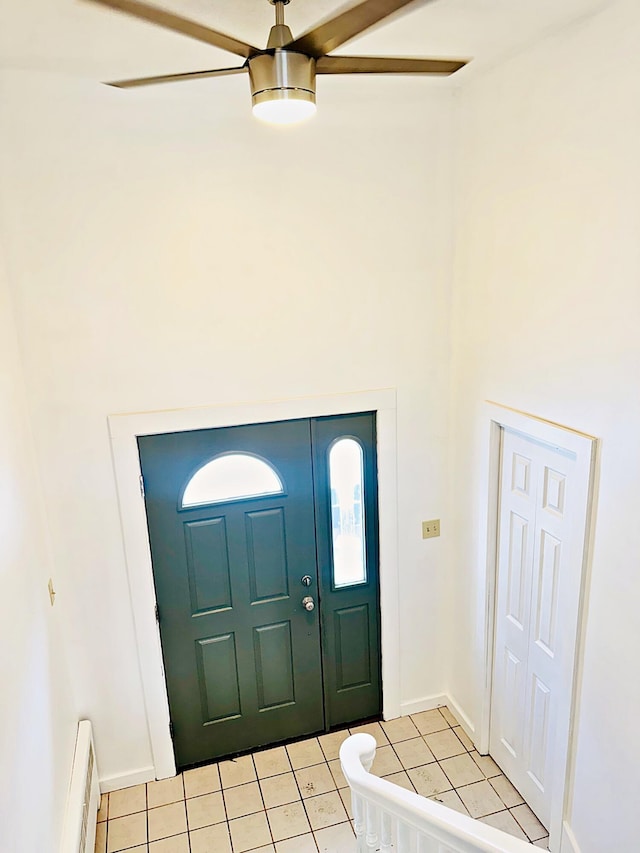 foyer with a baseboard heating unit, baseboards, ceiling fan, and light tile patterned floors