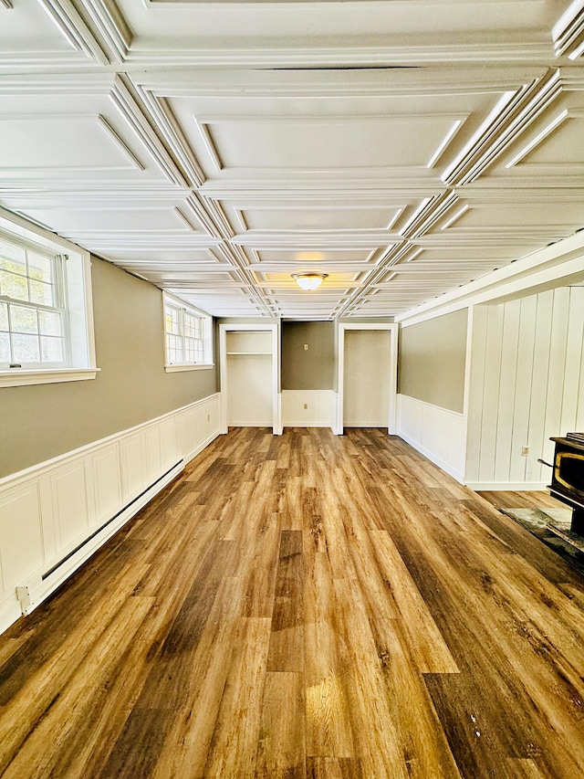 basement featuring wood finished floors, a wood stove, and baseboard heating