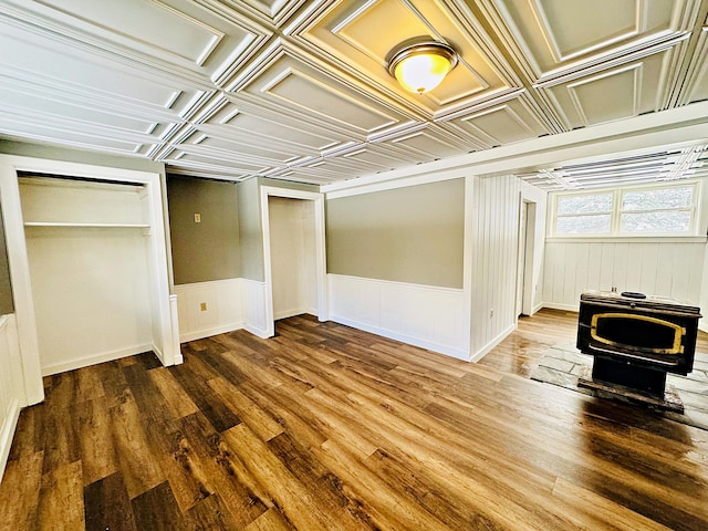 basement with wainscoting, a wood stove, and wood finished floors